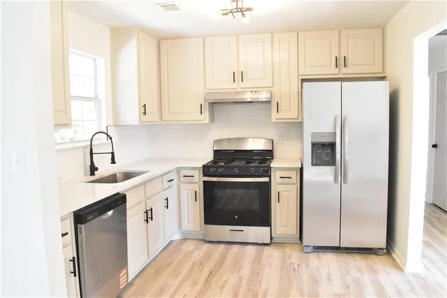 a kitchen with stainless steel appliances a sink cabinets and a refrigerator