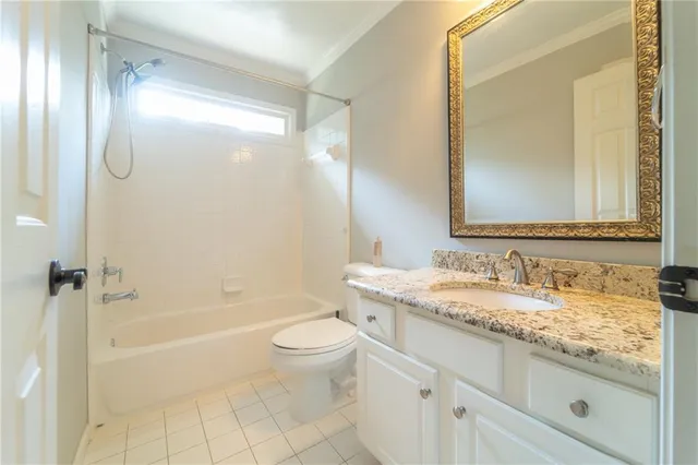a bathroom with a granite countertop bathtub shower sink vanity mirror and toilet