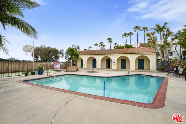 a view of a swimming pool with a lawn chairs under palm trees