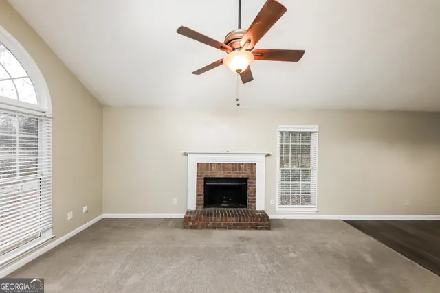 an empty room with windows and fireplace