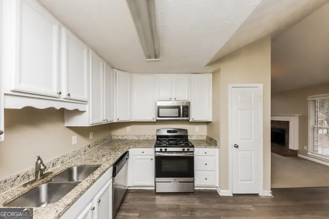 a kitchen with granite countertop a stove sink and cabinets