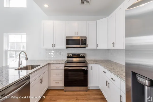 a kitchen with stainless steel appliances granite countertop white cabinets a stove a sink and dishwasher