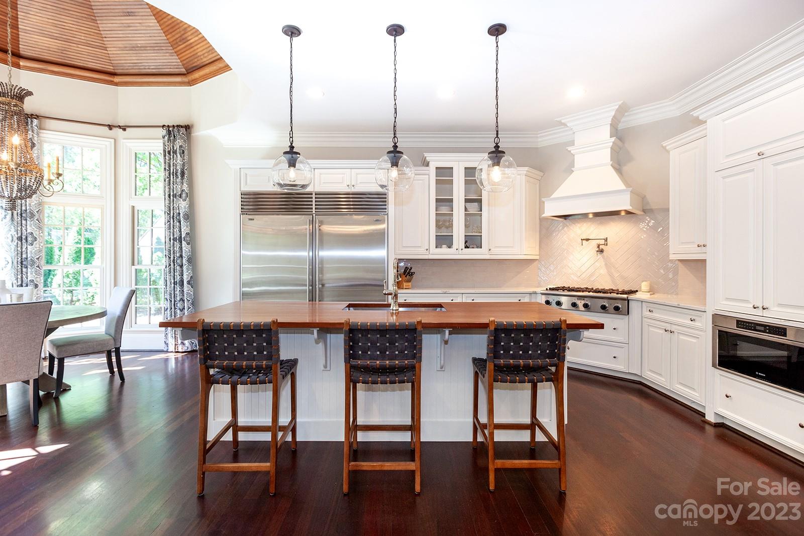 1925 Shoreham Drive Charlotte, NC 28211 - Photo 4 of 48 a kitchen with stainless steel appliances granite countertop a stove top oven a sink a dining table and chairs with wooden floor