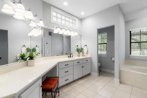 a spacious bathroom with a granite countertop sink a mirror and a bathtub with shower