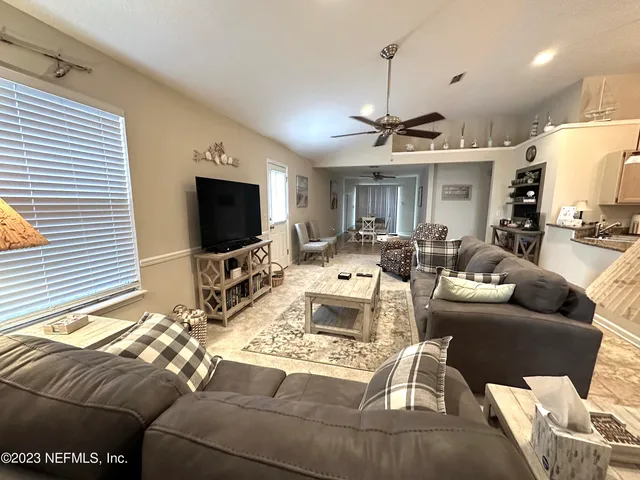 a living room with furniture a flat screen tv and a window