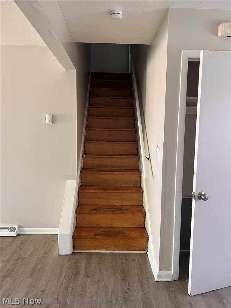 16350 Rockside Road Maple Heights, OH 44137 - Photo 16 of 34 Wood-finish staircase with white trim, complemented by light gray wall paint and wood-finish flooring