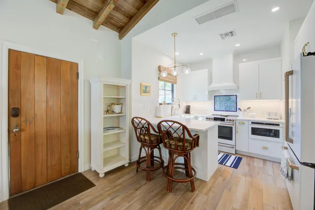 a kitchen with stainless steel appliances granite countertop a stove top oven a sink dishwasher a dining table and chairs with wooden floor