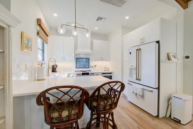 a kitchen with stainless steel appliances a refrigerator a sink dishwasher a stove with white cabinets and wooden floor