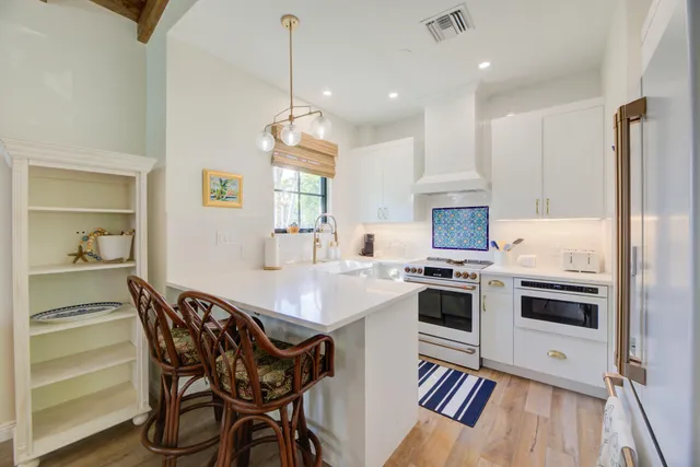 a kitchen with stainless steel appliances a stove a sink a refrigerator and a dining table