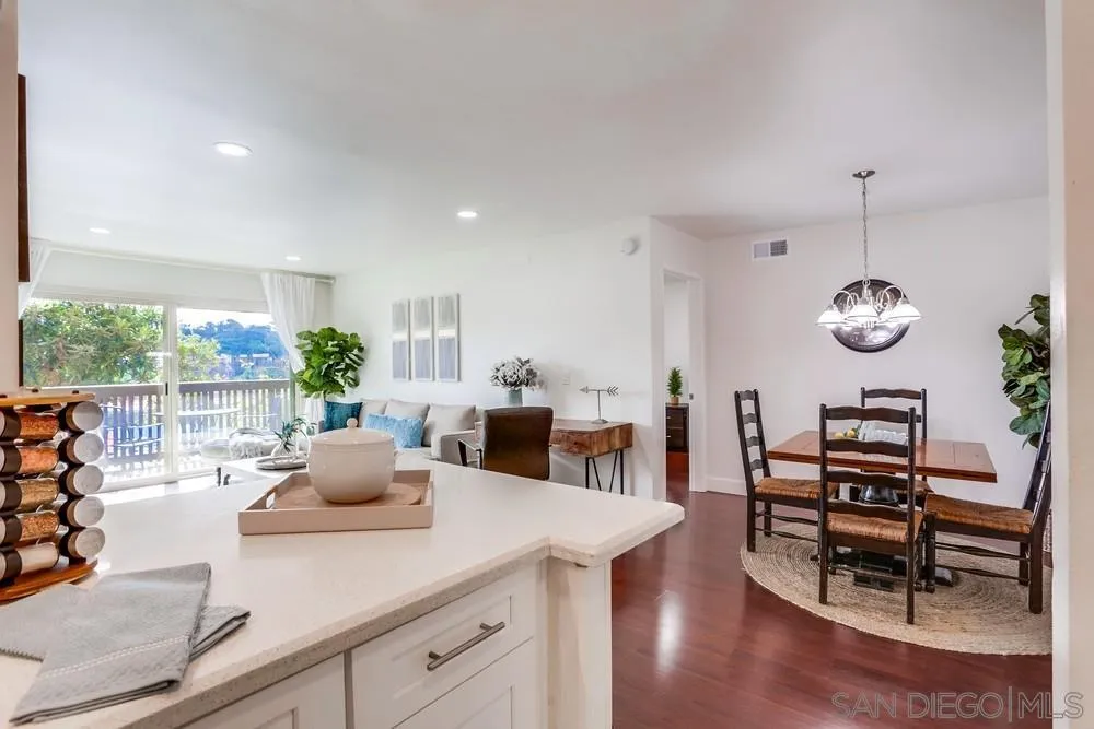 6314 Friars Road, Unit 116 San Diego, CA 92108 - Photo 12 of 36 a view of a dining room and livingroom with furniture wooden floor a rug a potted plant and a chandelier