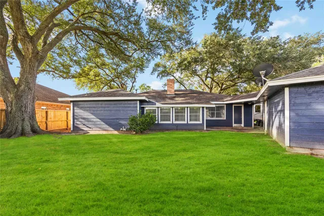 a view of a yard in front of a house with large trees