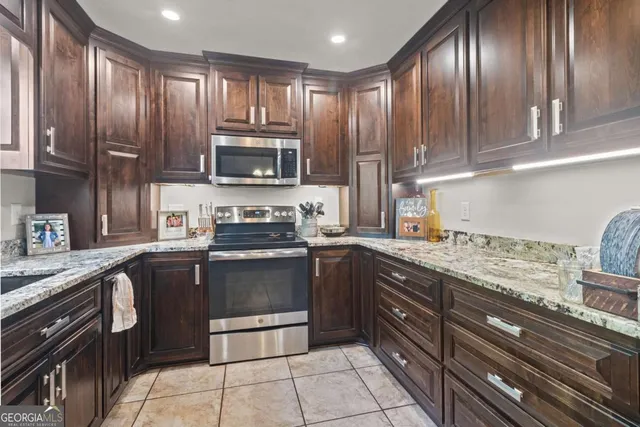 a kitchen with granite countertop a sink stainless steel appliances and a window