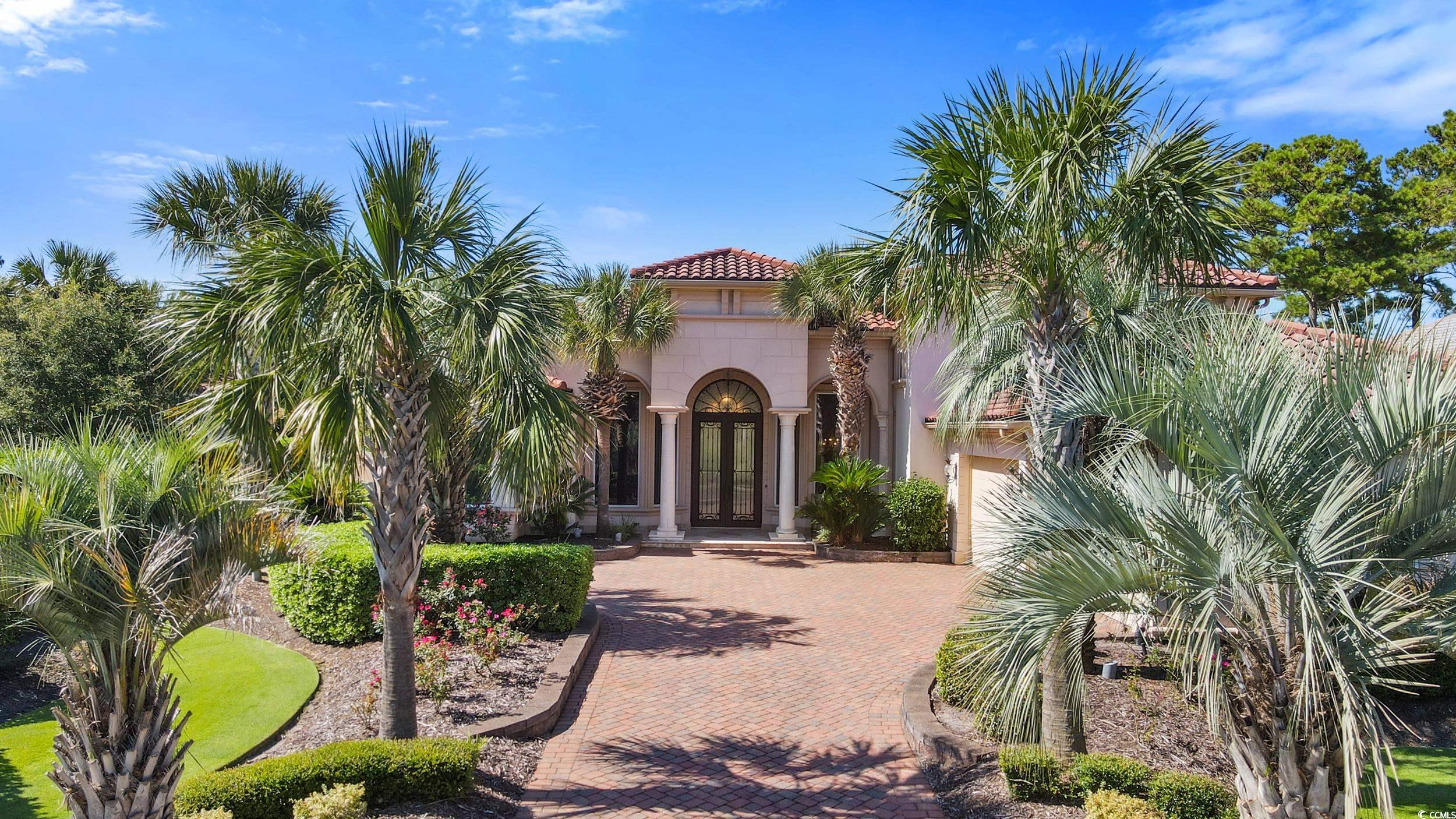Property entrance with a tile roof, stucco siding, french doors, and decorative driveway