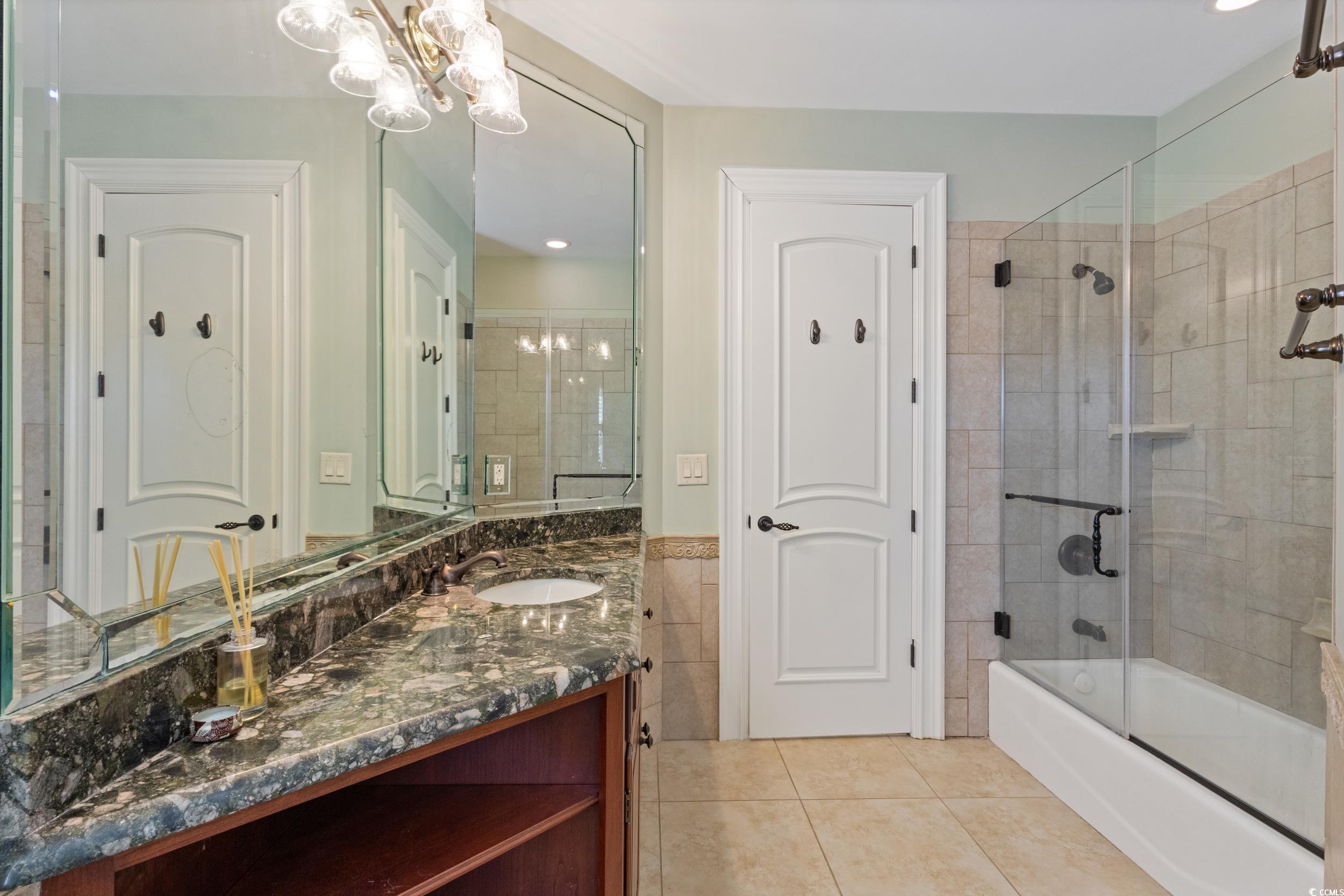 9237 Bellasera Circle Myrtle Beach, SC 29579 - Photo 22 of 34 Full bath featuring vanity, shower / bath combination with glass door, a chandelier, light tile patterned flooring, and tile walls