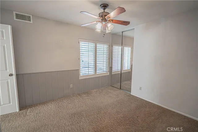 an empty room with windows and fan