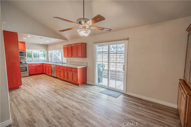 a view of an empty room with window wooden floor and a kitchen