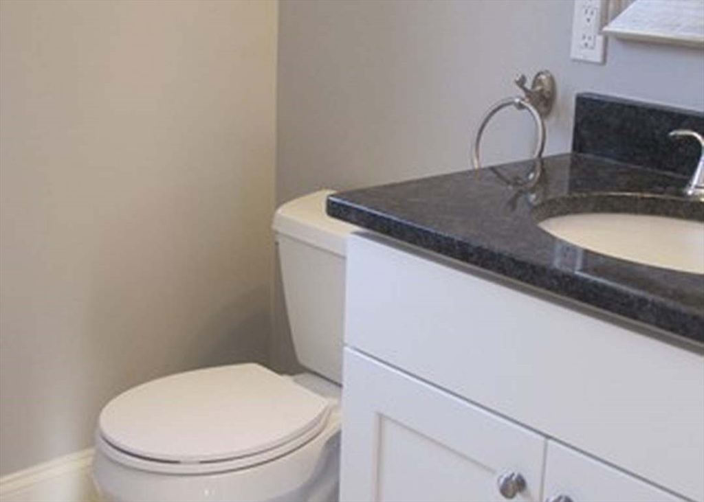 210 South Quinsigamond Avenue, Unit 1 Shrewsbury, MA 01545 - Photo 10 of 11 a bathroom with a granite countertop toilet sink and mirror