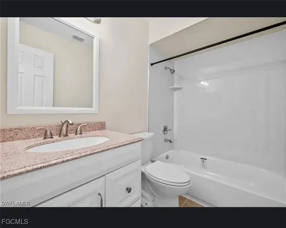 a bathroom with a granite countertop sink mirror vanity bathtub and a toilet