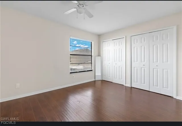 an empty room with wooden floor chandelier fan and windows