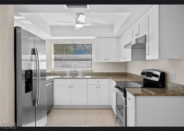 a kitchen with stainless steel appliances granite countertop a stove a sink and a refrigerator