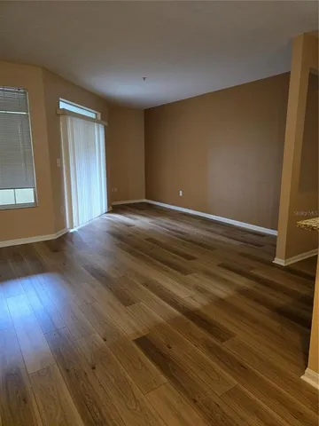 a view of an empty room with wooden floor and a window