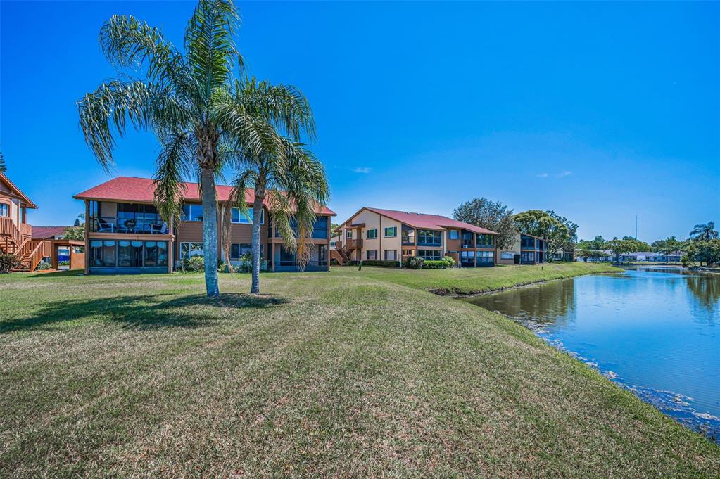 3847 Lighthouse Way, Unit 3847 New Port Richey, FL 34652 - Photo 14 of 89 a front view of a house with a yard and a pond