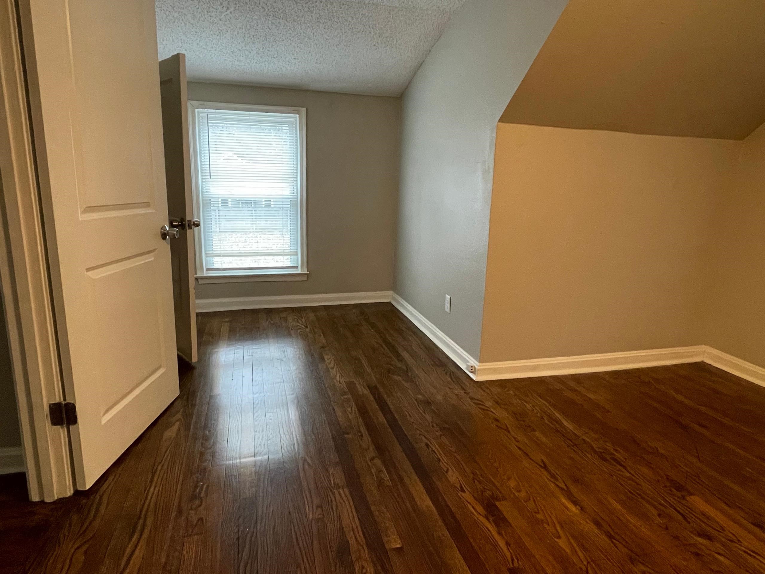 984 East Raines Road Memphis, TN 38116 - Photo 11 of 19 an empty room with wooden floor and windows with curtains