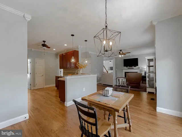 a dining room with wooden floor a chandelier a glass table and chairs