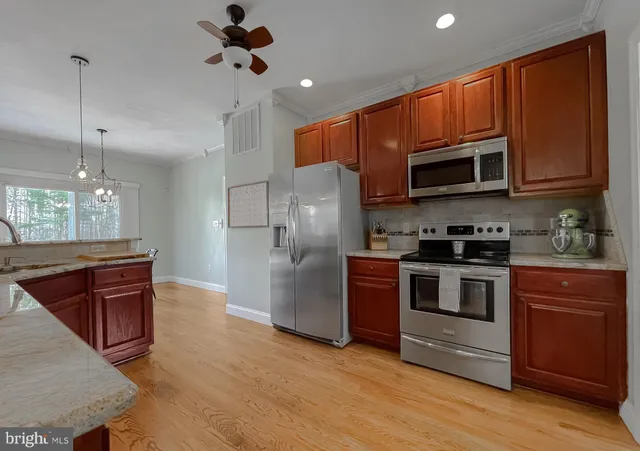 a kitchen with stainless steel appliances granite countertop a sink a stove and a wooden floors
