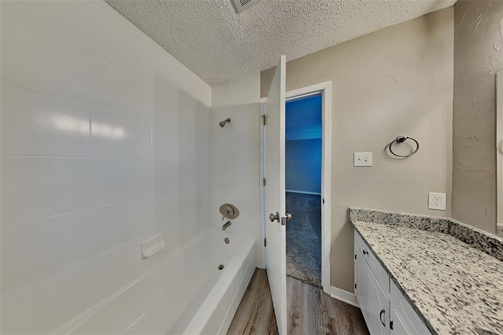 6432 Ridglea Drive Watauga, TX 76148 - Photo 11 of 18 Bathroom featuring shower / bath combination, a textured ceiling, vanity, and dark wood finished floors