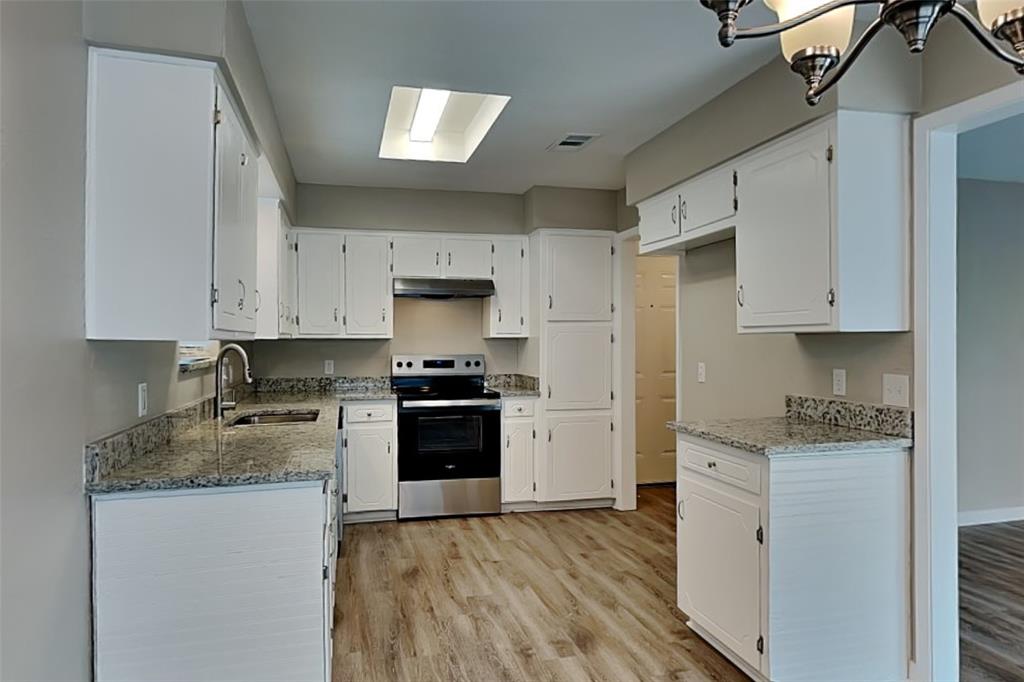 6432 Ridglea Drive Watauga, TX 76148 - Photo 4 of 18 Kitchen with light stone countertops, stainless steel electric range, white cabinetry, and light wood-style floors