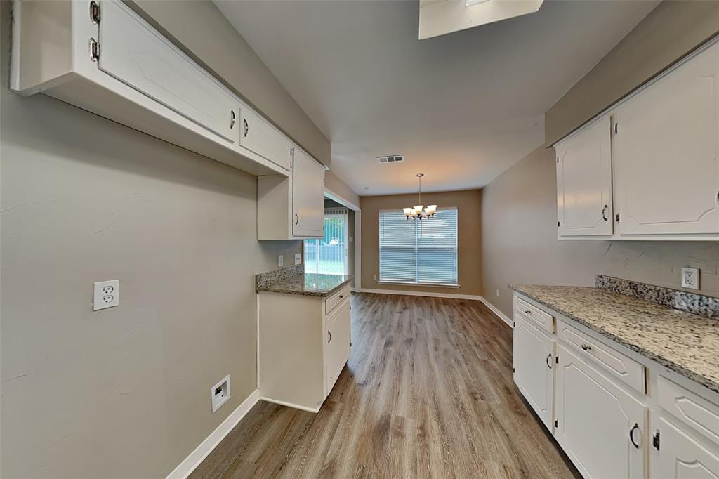 6432 Ridglea Drive Watauga, TX 76148 - Photo 5 of 18 Kitchen with white cabinetry, light stone counters, light wood-style flooring, pendant lighting, and a chandelier