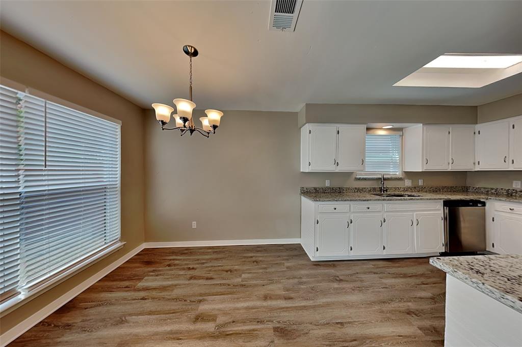6432 Ridglea Drive Watauga, TX 76148 - Photo 6 of 18 Kitchen featuring light stone counters, light wood-style floors, white cabinetry, stainless steel dishwasher, and decorative light fixtures