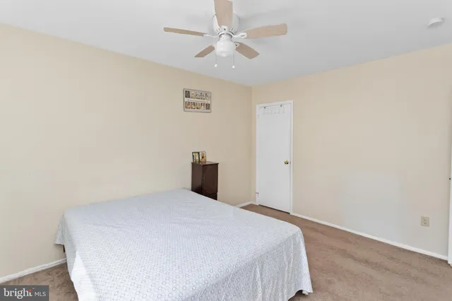 a spacious bedroom with a bed and a chandelier fan