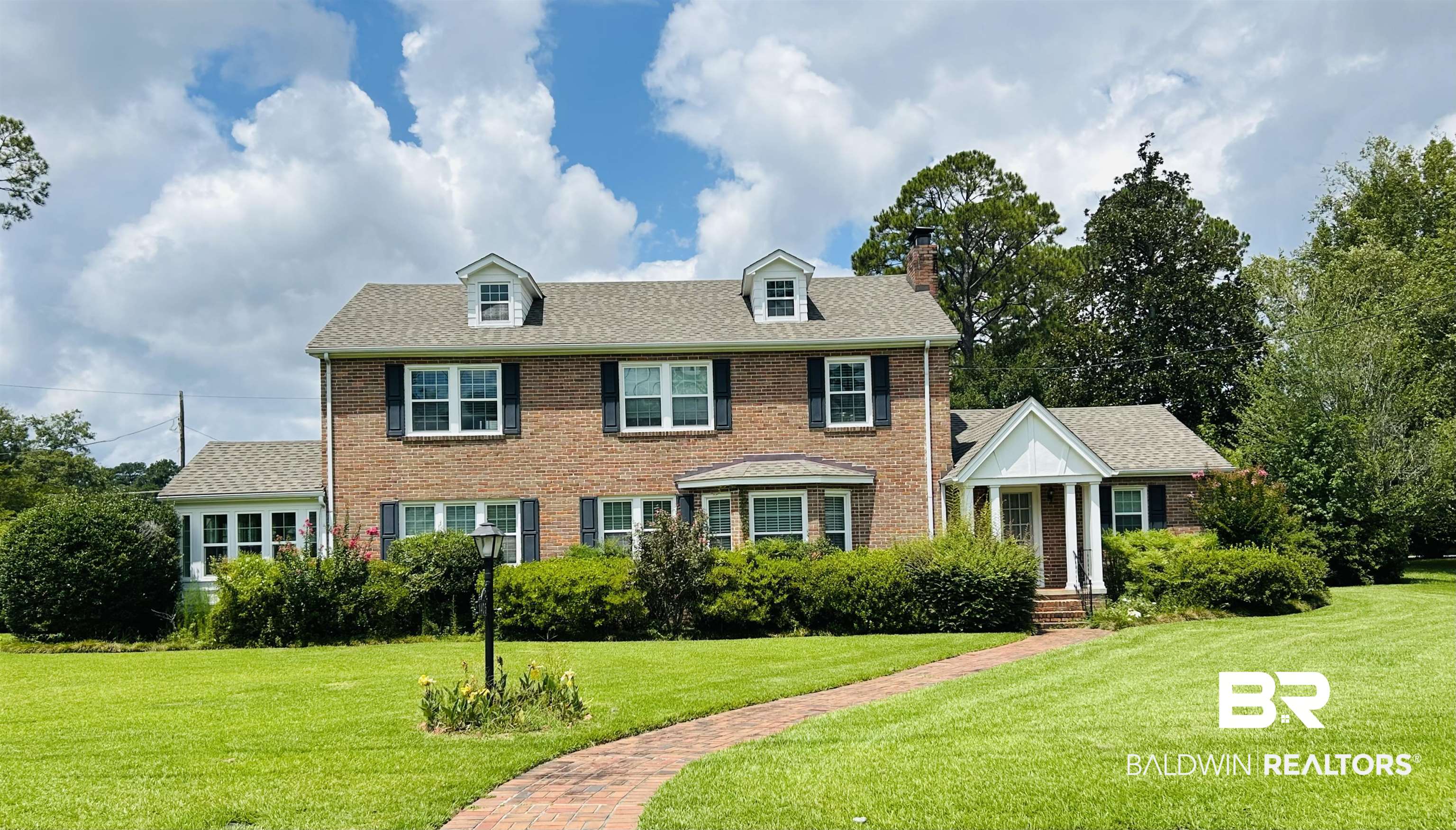 1405 Escambia Avenue Brewton, AL 36426 - Photo 1 of 16 Colonial-style house with a front lawn, brick siding, a chimney, and a shingled roof