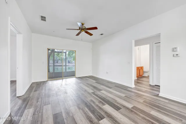 a view of empty room with wooden floor and fan