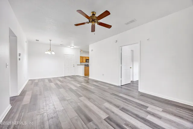 a view of empty room with wooden floor and ceiling fan