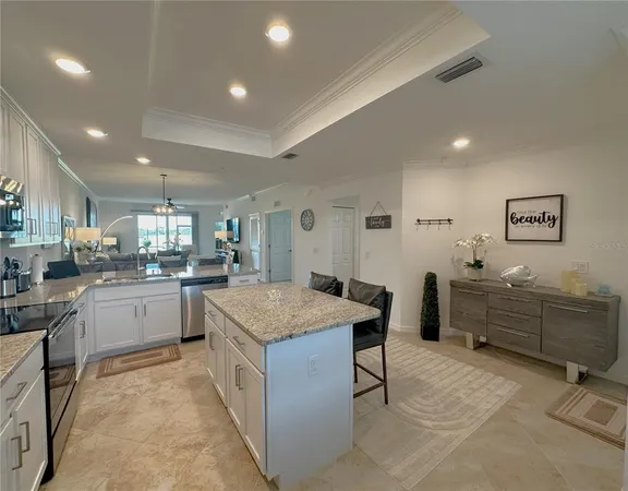 a open dining room with stainless steel appliances kitchen island granite countertop a table chairs and a refrigerator