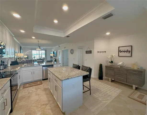 a open dining room with stainless steel appliances kitchen island granite countertop a table chairs and a refrigerator
