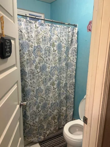 a white toilet sitting next to a shower curtain