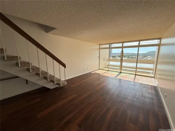 a view of an empty room with wooden floor and windows