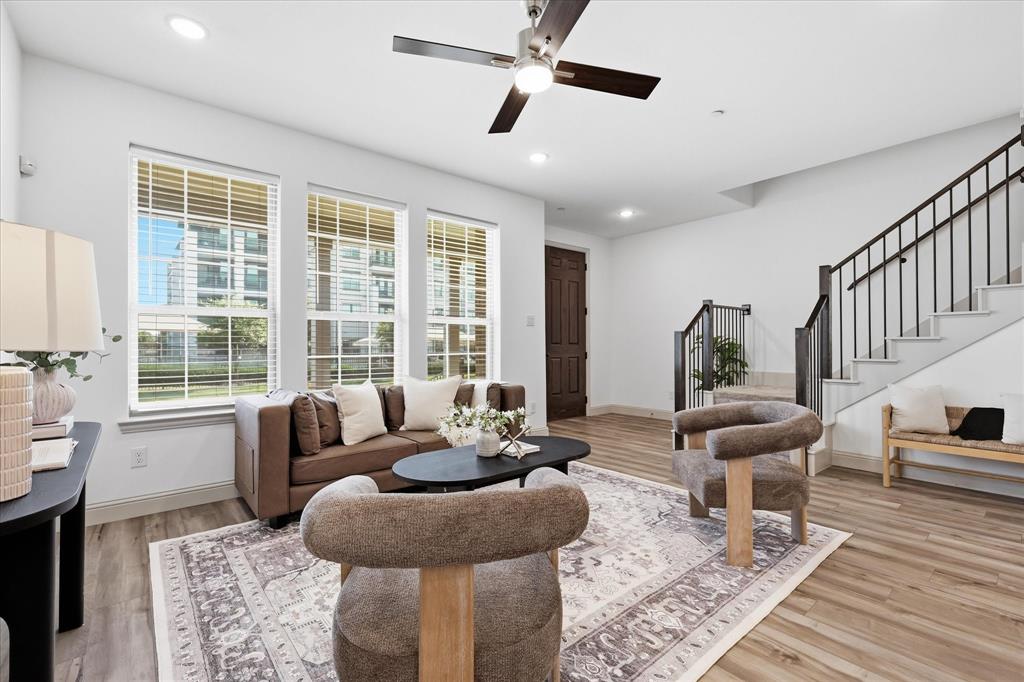 6141 Roper Road McKinney, TX 75070 - Photo 8 of 35 Spacious living area featuring ample natural light, wood-finish flooring, a modern ceiling fan, and a staircase with contemporary railing