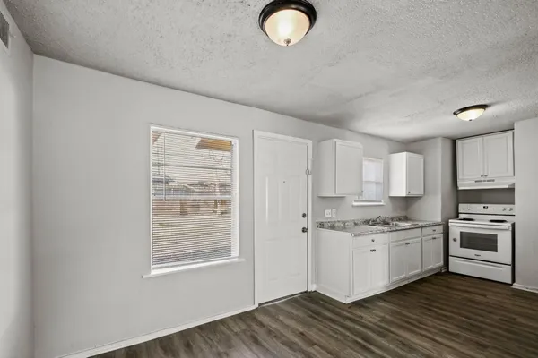 a kitchen with stainless steel appliances granite countertop a stove a sink and white cabinets with wooden floor