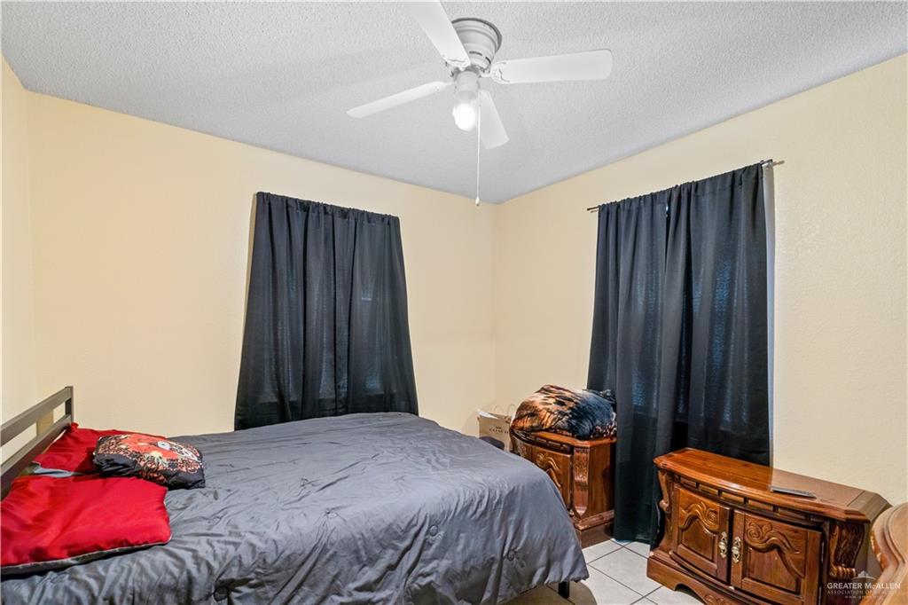 106 Rosa Priego Street Donna, TX 78537 - Photo 10 of 25 Bedroom with ceiling fan, a textured ceiling, and light tile patterned floors