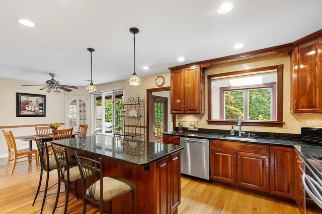 a kitchen with stainless steel appliances granite countertop wooden cabinets a stove a sink a dining table and chairs