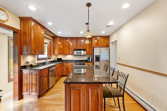 a kitchen with stainless steel appliances granite countertop a stove top oven a sink dishwasher a dining table and chairs with wooden floor