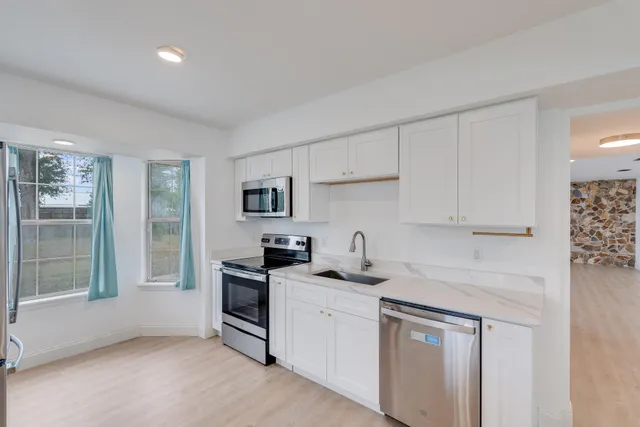 a kitchen with stainless steel appliances granite countertop white cabinets and window