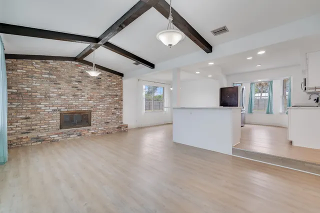 an empty room with wooden floor and a fireplace