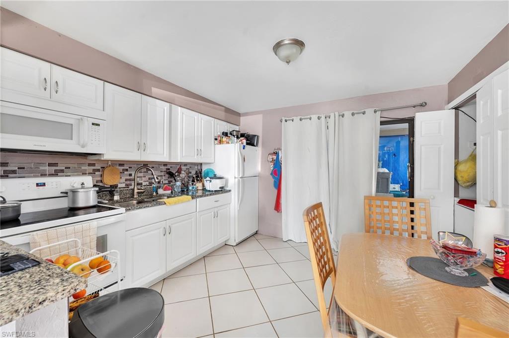 19133 Tangerine Road Fort Myers, FL 33967 - Photo 4 of 17 Kitchen with light hardwood / wood-style floors, appliances with stainless steel finishes, white cabinetry, and light stone counters
