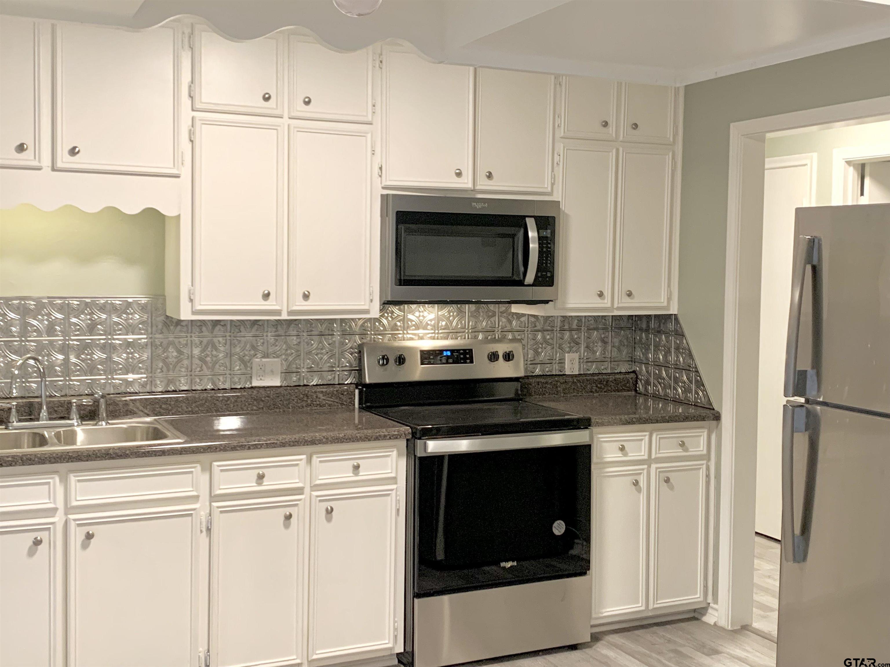 901 Cliff Street Quitman, TX 75783 - Photo 4 of 15 a kitchen with stainless steel appliances granite countertop white cabinets a refrigerator a stove a sink and white cabinets